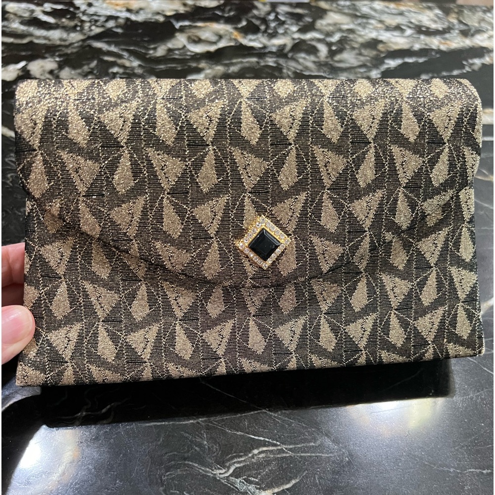 Gold and black purse with long strap and rhinestone snap closure.
